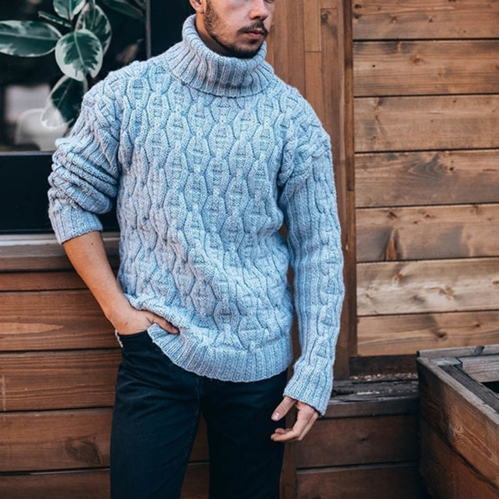 Homme portant un pull col roulé élégant en gros tricot torsadé, parfait pour un style hivernal chic.