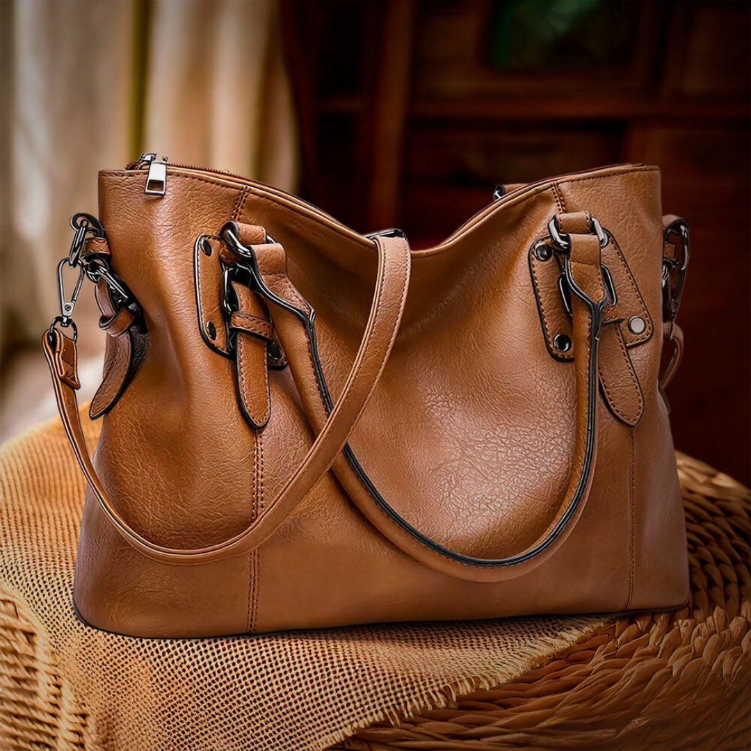 Détail du sac bandoulière en cuir marron, montrant la texture raffinée et le fermoir élégant.