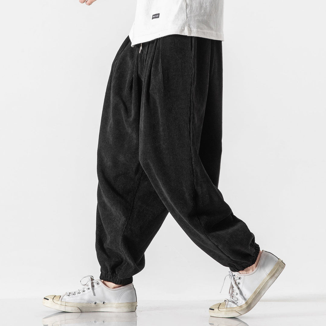 Homme portant un pantalon large gris, coupe décontractée moderne, offrant un confort absolu.
