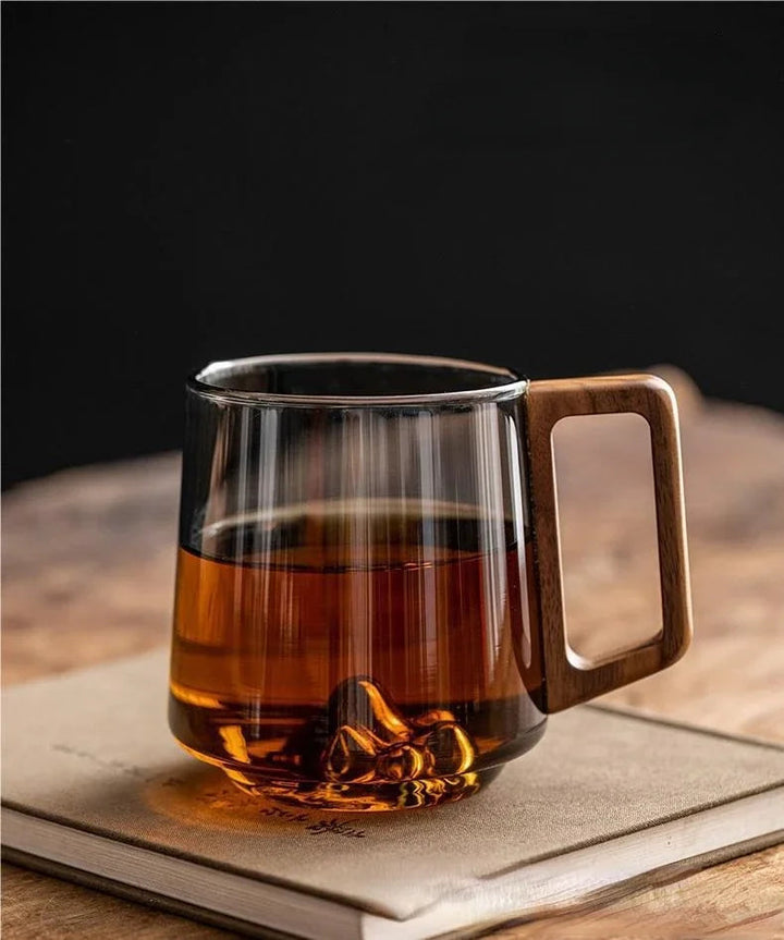 Tasse à café et thé en verre clair avec poignée en bois, parfaite pour savourer vos boissons chaudes.