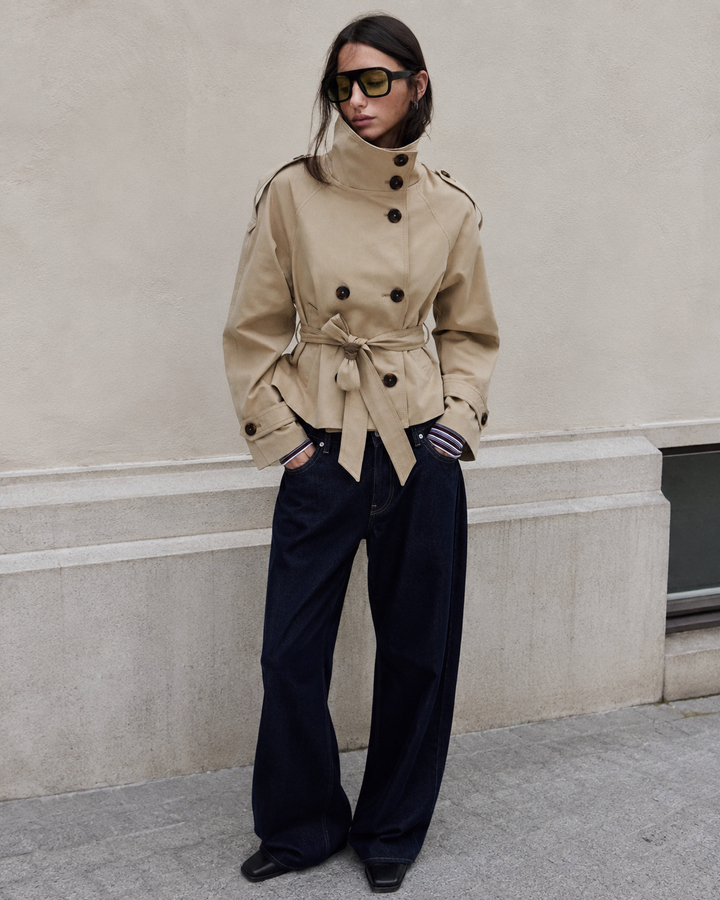 Trench-coat femme kaki élégant, coupe courte, col montant structuré. Ceinture ajustée pour une silhouette chic.