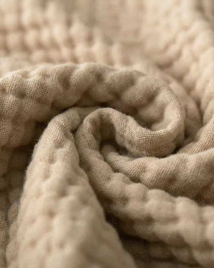 Plaid en mousseline de coton respirant, parfait pour un confort naturel sur lit ou canapé.