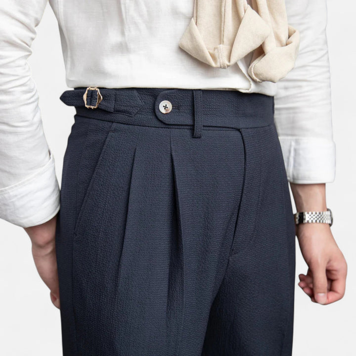 Homme portant un pantalon taille haute marine, look classique et élégant. Parfait pour le bureau moderne.