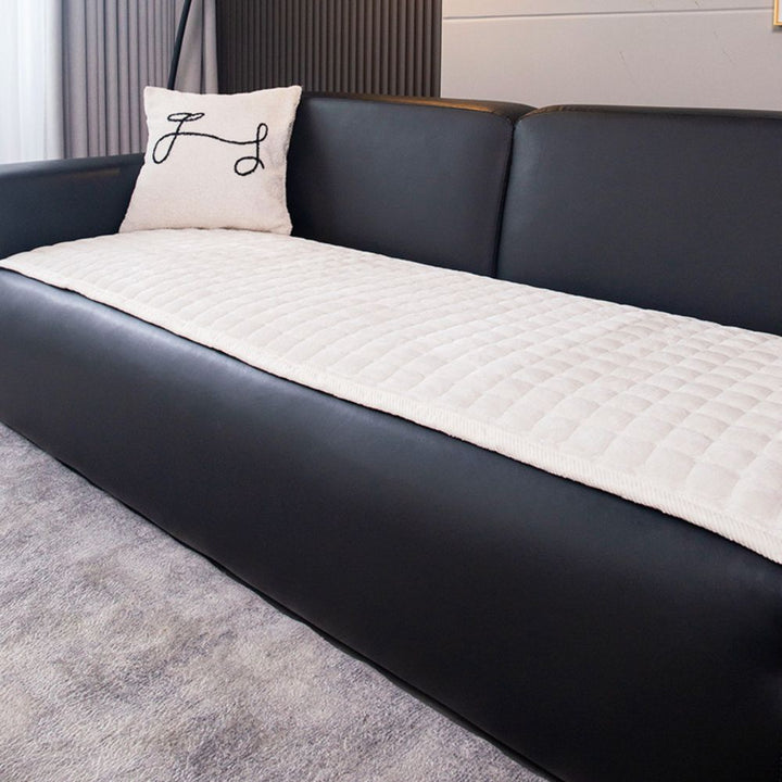 Texture douce d'une housse de canapé en peluche matelassée, apportant chaleur et confort au salon.