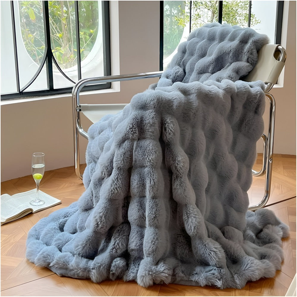 Couverture polaire fausse fourrure sur un canapé, invitant à la douceur et chaleur cocooning.