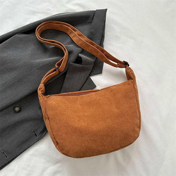 Femme portant un sac banane velours noir en bandoulière, mode hiver, look tendance et confortable.