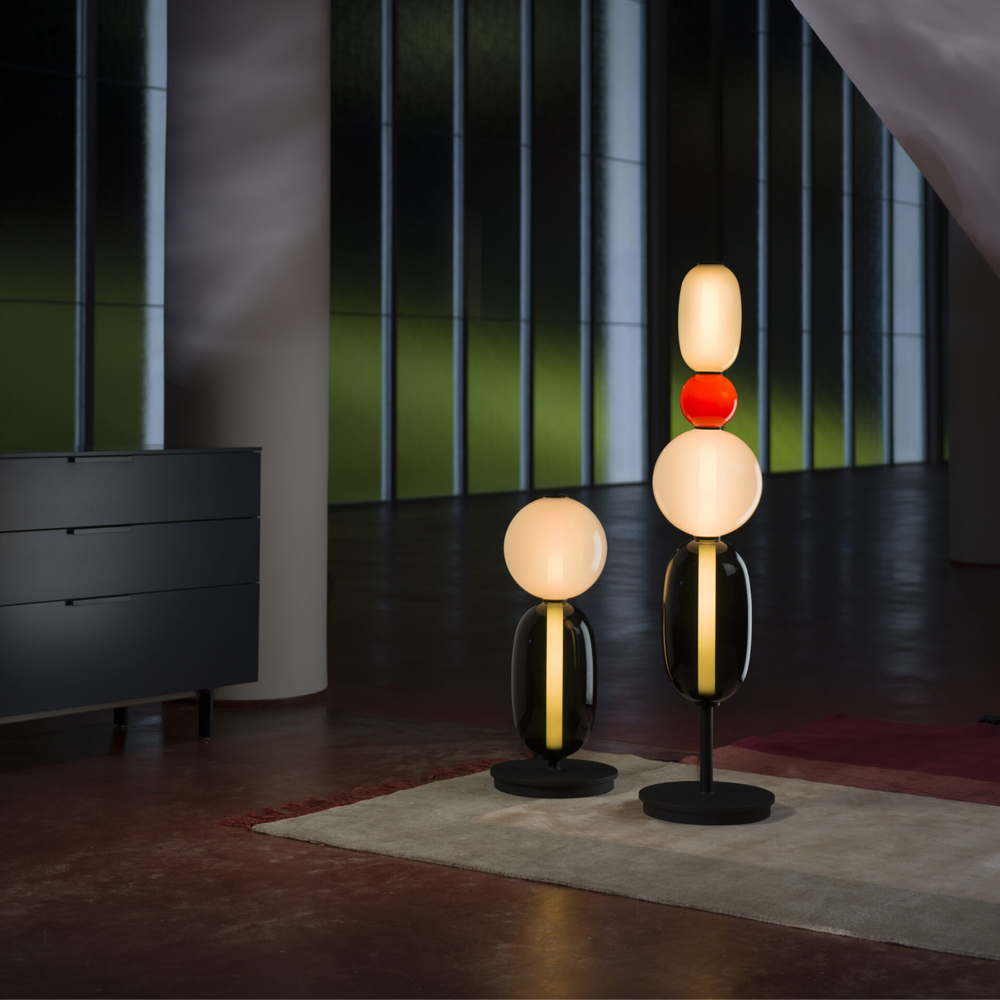 Luminaire artistique sur pied, diffuse une lumière chaleureuse avec son verre teinté.