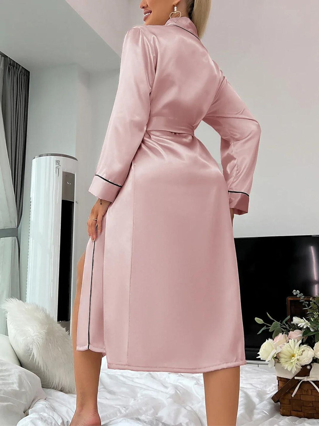 Femme souriante portant un peignoir en satin rose, chic, confortable pour le matin.