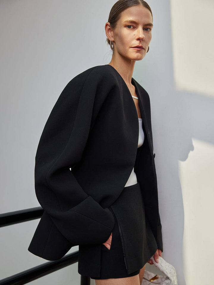 Blazer femme noir élégant sans revers, coupe droite moderne avec boutons. Idéal pour une tenue de bureau chic.