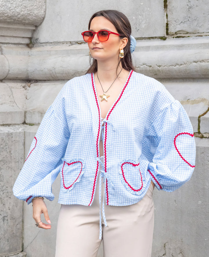 Blouse femme vichy rouge à carreaux, ouverte avec liens à nouer sur le devant, manches longues, ourlet festonné.