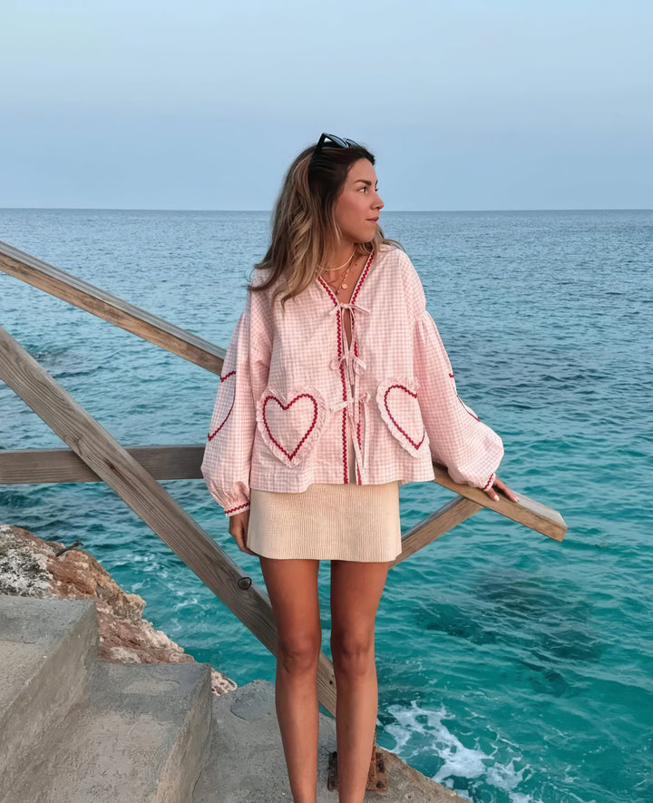 Blouse vichy femme décontractée et élégante, avec col ouvert et liens, manches longues festonnées, parfaite pour l'été.