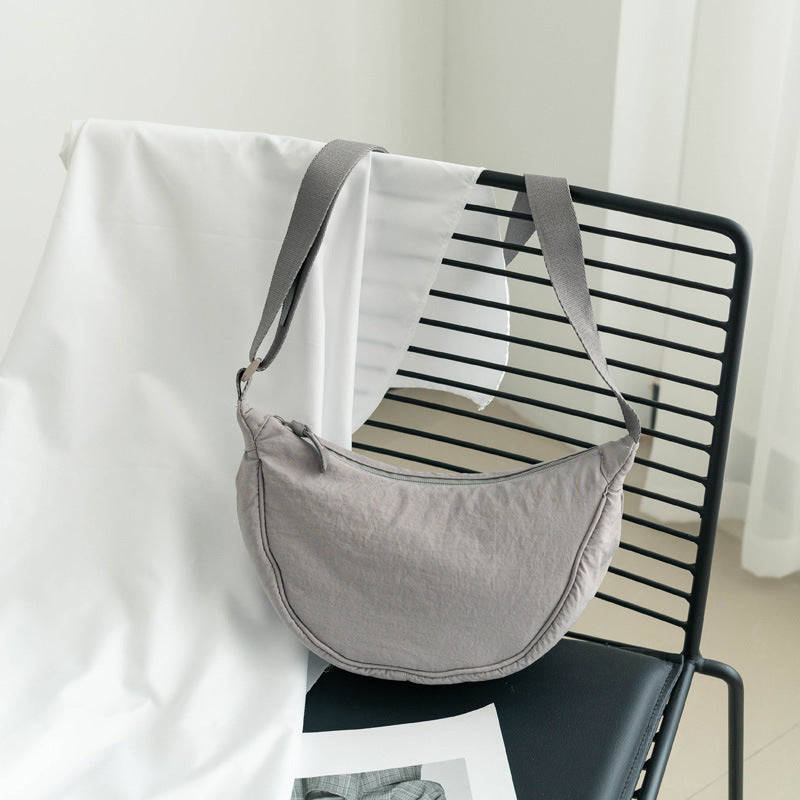 Sac bandoulière gris femme en nylon, forme demi-lune. Accessoire ajustable et décontracté.