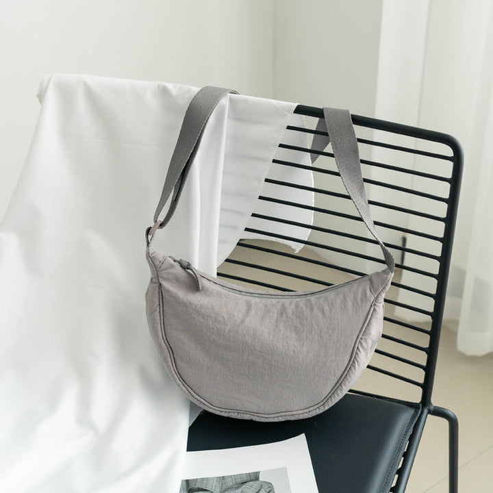 Sac bandoulière gris femme en nylon, forme demi-lune. Accessoire ajustable et décontracté.