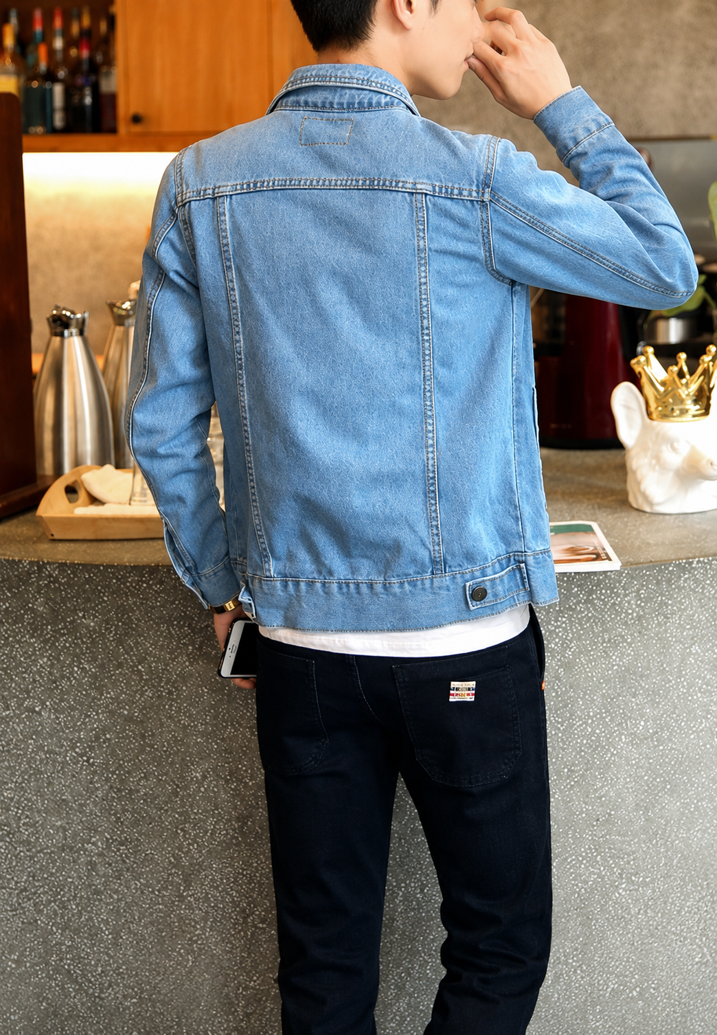Jeune homme en veste en jean délavée, marchant en ville, style urbain et décontracté, mode masculine moderne.