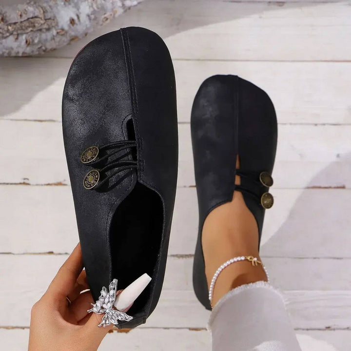 Femme portant chaussures plates élégantes, confort quotidien garanti. Style décontracté sans lacets pour printemps/été.