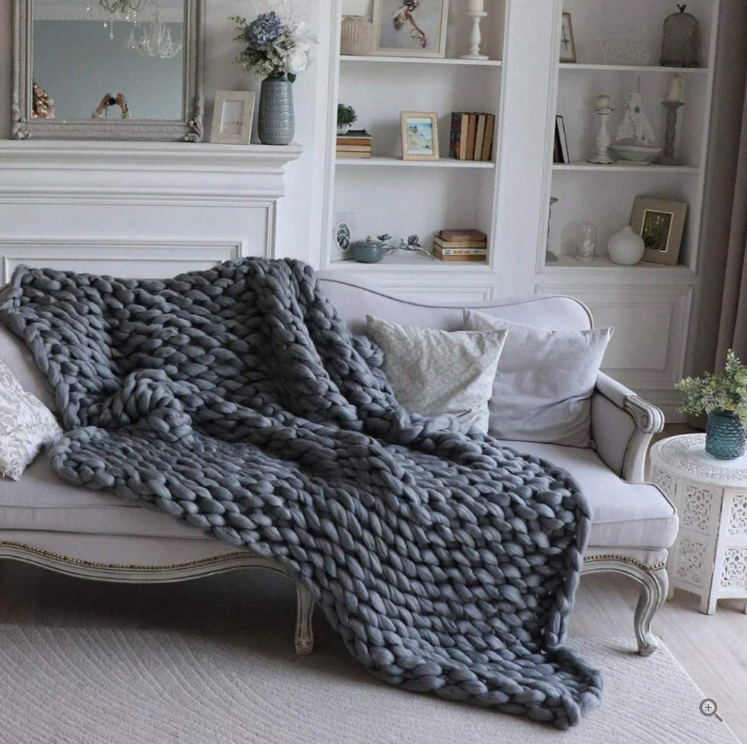 Jeté de canapé en laine mérinos tricotée artisanale, ajoutant une touche élégante et cosy à votre décoration intérieure.