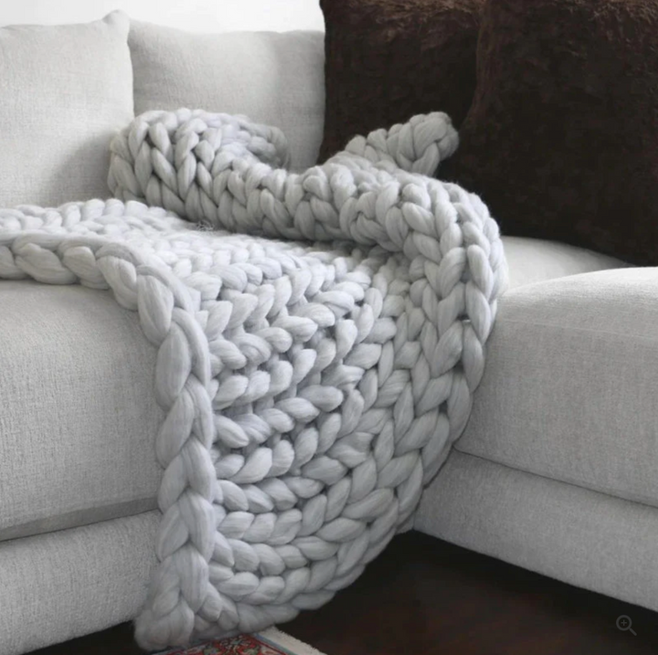 Plaid artisanal en pure laine mérinos, tricoté pour une chaleur enveloppante et un style élégant dans le salon.