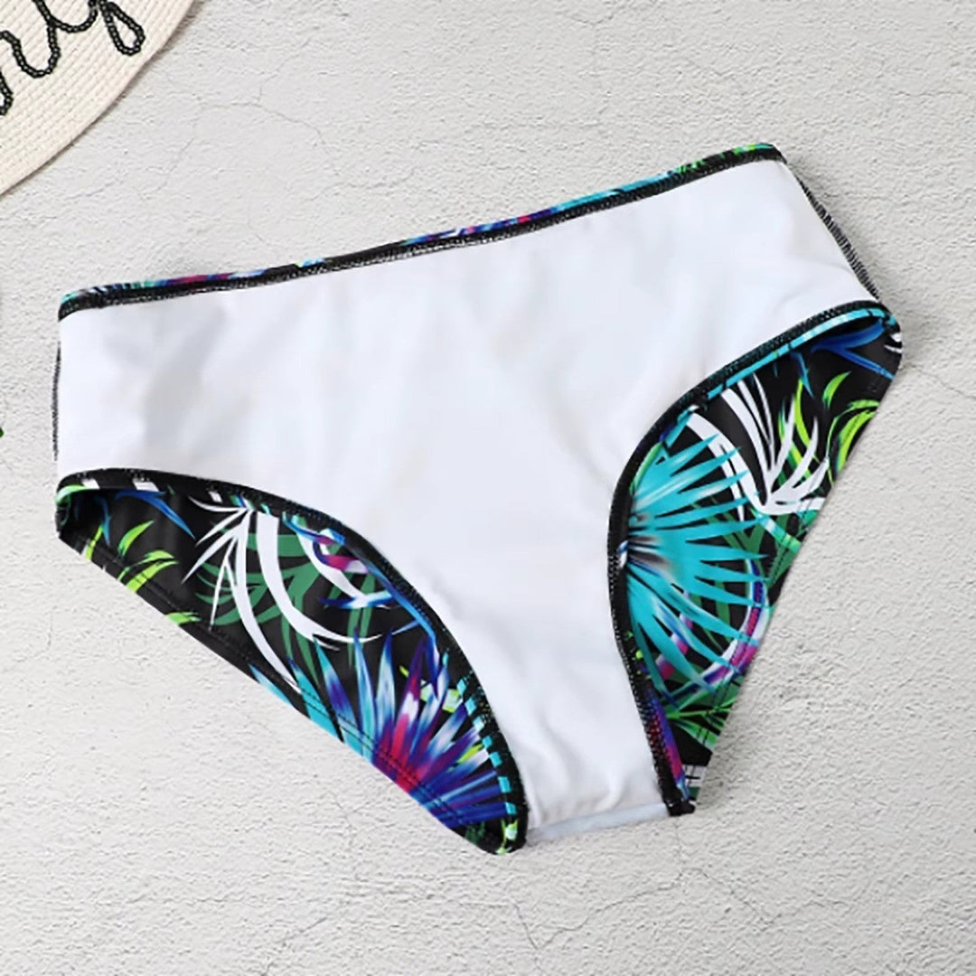 Femme portant un bikini taille haute à imprimé tropical sur une plage ensoleillée. Maillot de bain élégant d'été.
