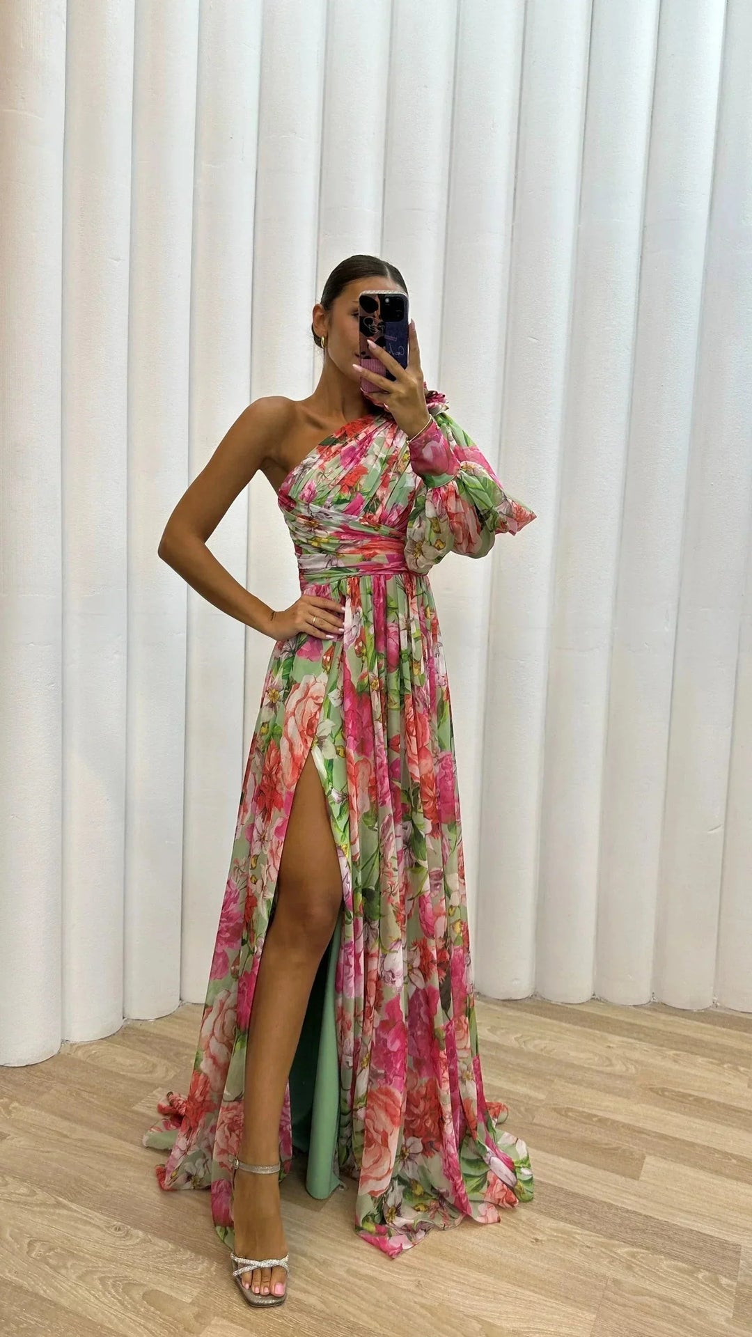 Robe longue asymétrique fleurie femme de profil. Met en valeur les manches bouffantes et l'imprimé floral.