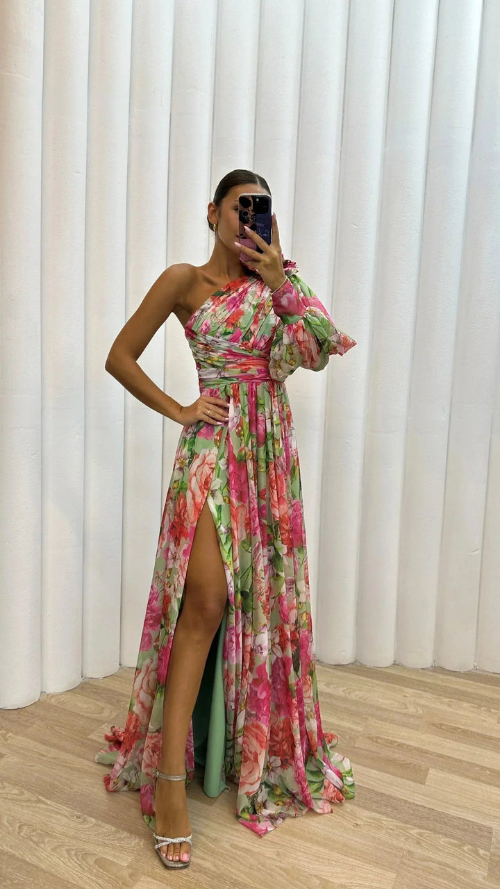Robe longue asymétrique fleurie femme de profil. Met en valeur les manches bouffantes et l'imprimé floral.