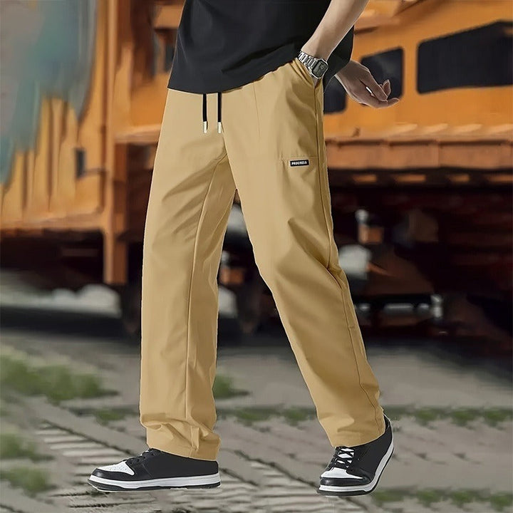 Homme portant un pantalon droit décontracté beige, élégant et moderne, parfait pour le quotidien ou les loisirs.