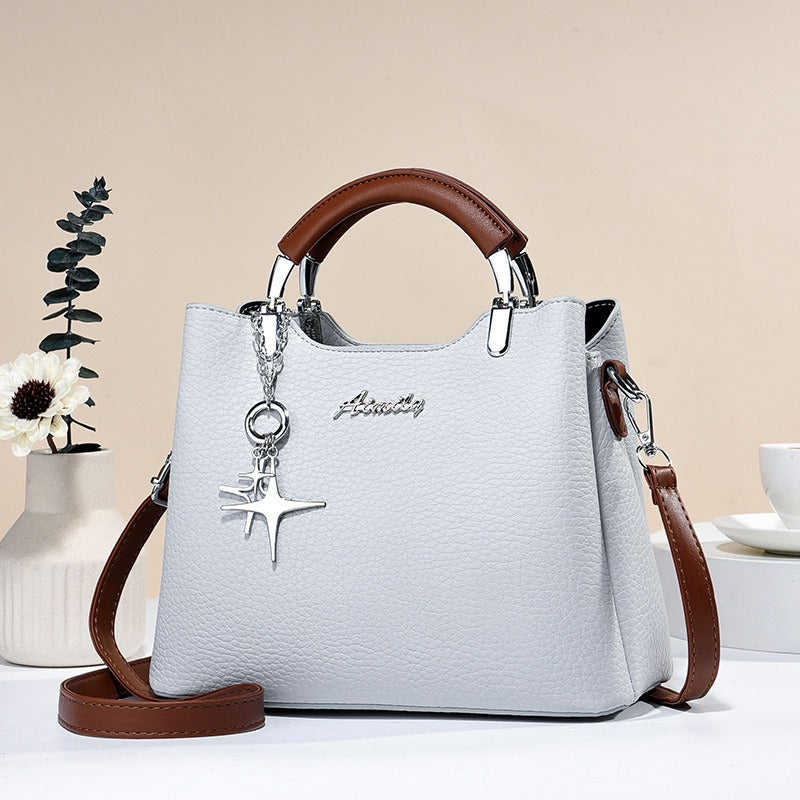 Élégant sac à main femme en simili-cuir avec pendentif décoratif, accessoire mode chic.