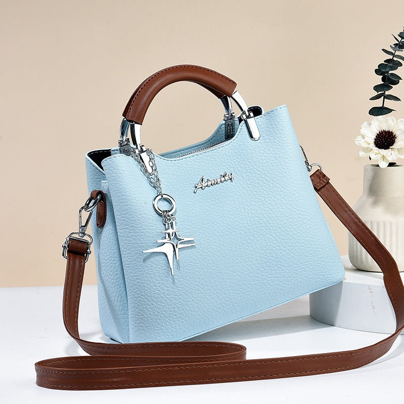 Accessoire mode femme: sac à main chic en simili-cuir avec pendentif, idéal pour un look d'été.
