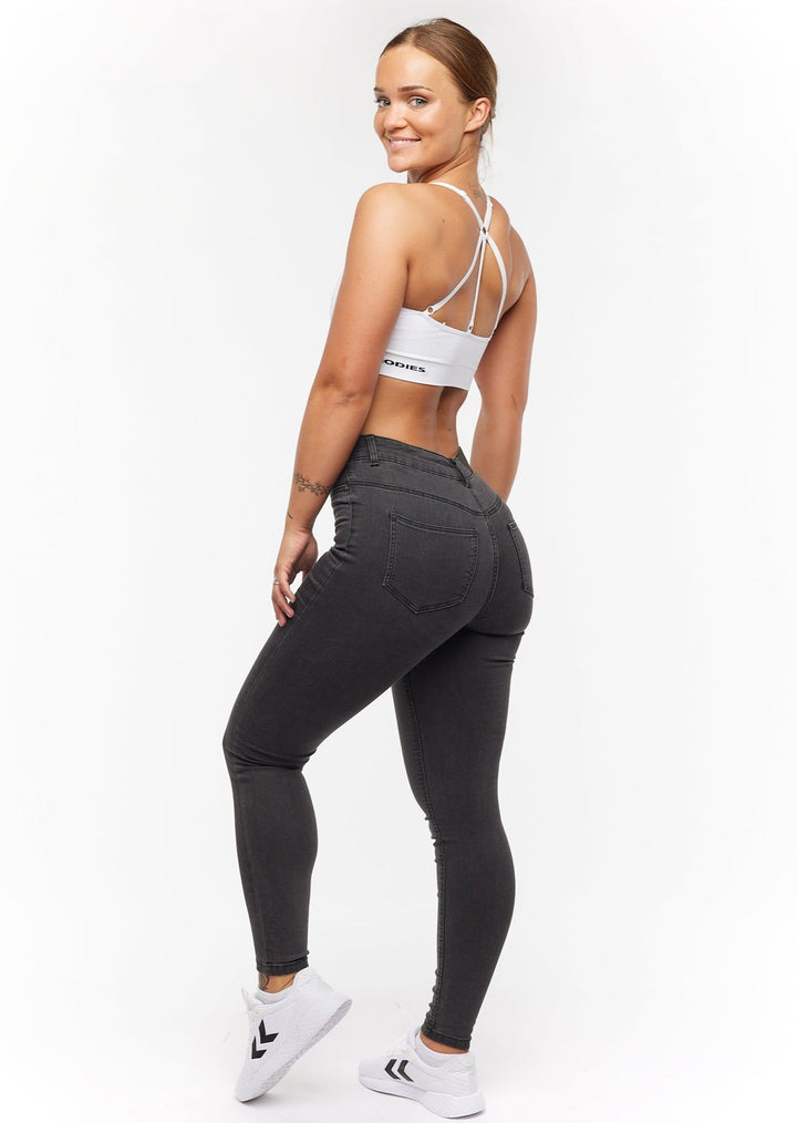 Jean femme skinny taille haute en denim bleu brut, avec surpiqûres et coupe ajustée tendance.