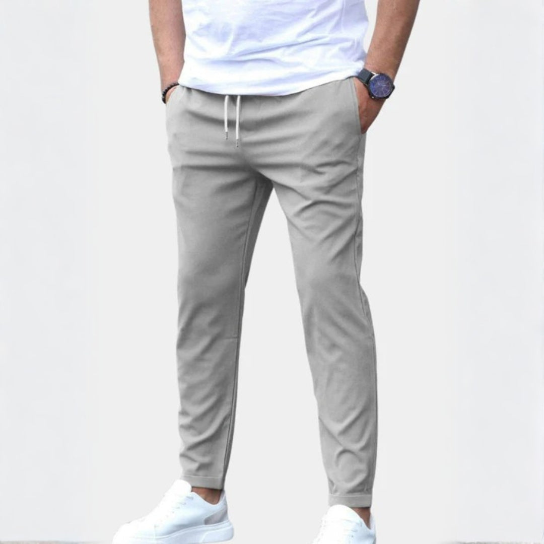 Homme marchant en pantalon chino gris, soulignant sa polyvalence et son confort pour la mode masculine.