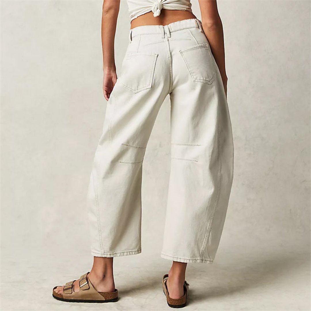 Femme souriante en pantalon large denim, look printanier décontracté et confortable.