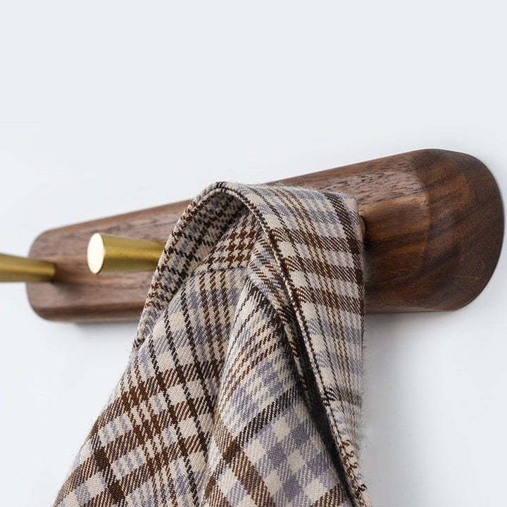 Rangement mural minimaliste en bois de hêtre avec crochets en laiton poli pour le couloir.