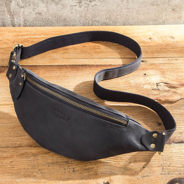 Homme moderne portant un sac banane en cuir noir à la taille, accessoire tendance pour un look décontracté.