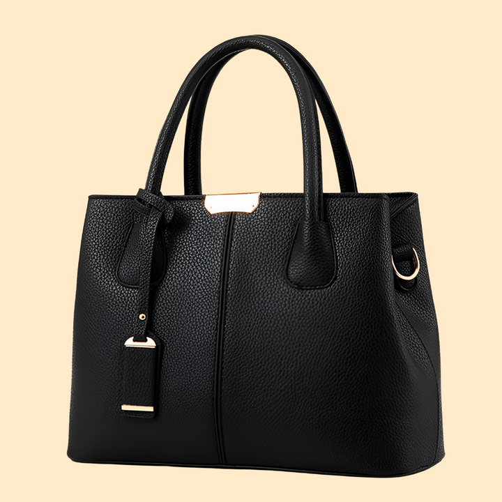 Sac femme structuré, forme rigide, avec pompon. Sac porté main élégant pour un look raffiné et moderne.